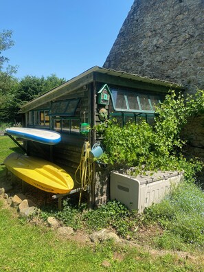 Una cabaña rústica con un porche pequeño, un comedero para pájaros y un kayak.
