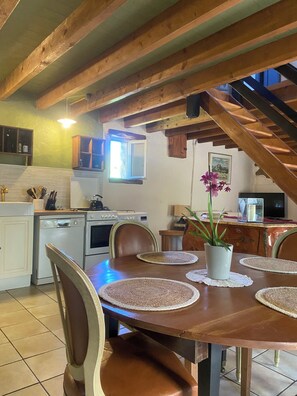 A dining area with a wooden table, chairs, and a potted plant.