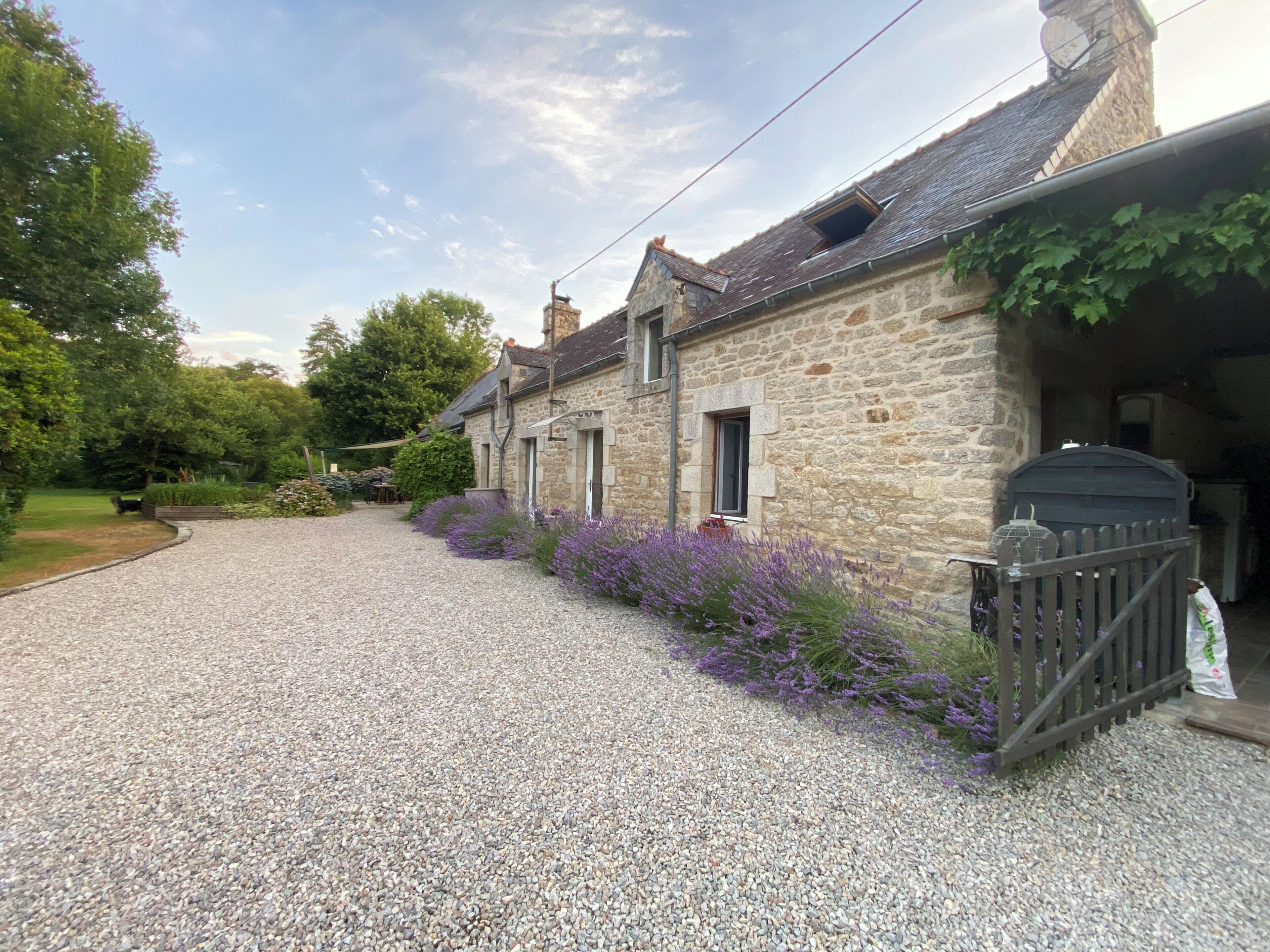 A stone building with a gravel driveway and a wooden fence.