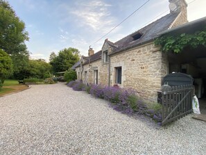 A stone building with a gravel driveway and a wooden fence.