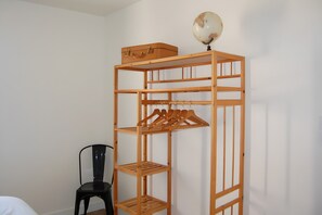 Uma unidade de armazenamento de madeira com vários níveis, com um globo no topo, uma mala e uma cadeira preta em um quarto com paredes brancas.