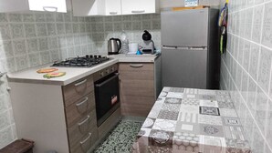 Cuina compacta amb fogó de gas, cafetera, nevera i rajoles amb un disseny original.