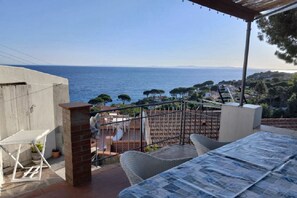 Una terrazza con vista sul mare, un tavolo, sedie e un pergolato.