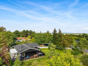 A residential area with multiple houses, a clear sky, and a lush green landscape.