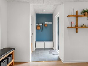 Ein Flur mit blauer Akzentwand, einer Bank, einem Kleiderständer und einem Regal mit Dekoration.