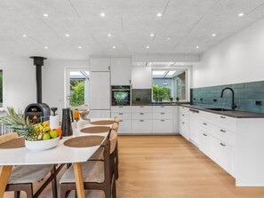 A modern kitchen with white cabinetry, a central island, and a built-in oven.