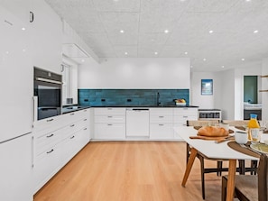Eine moderne Küche mit weißen Schränken, einem schwarzen Ofen und einer blauen Rückwand.