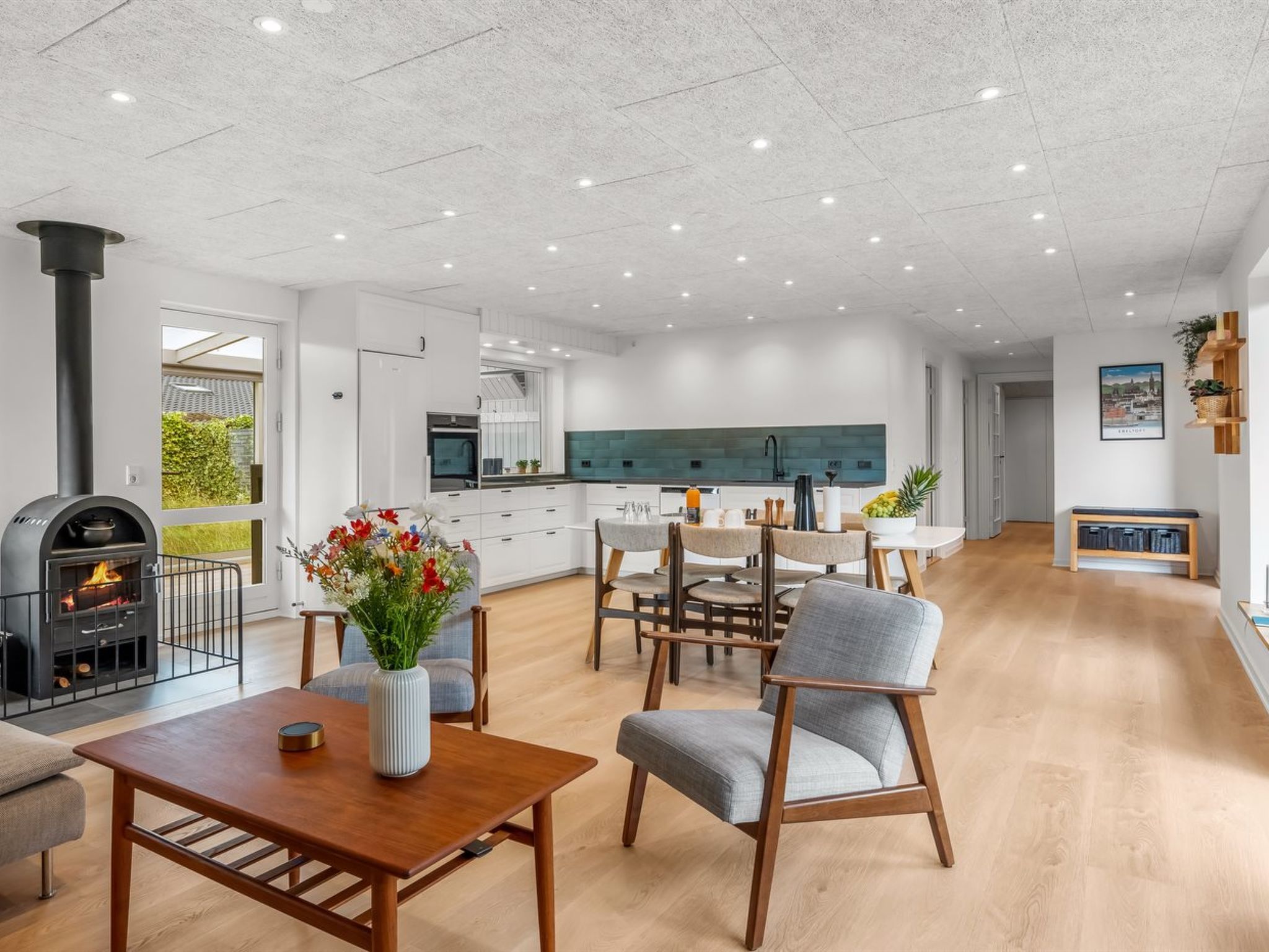 A modern kitchen with white cabinets, a black stove, and a dining area with a wooden table and grey chairs.