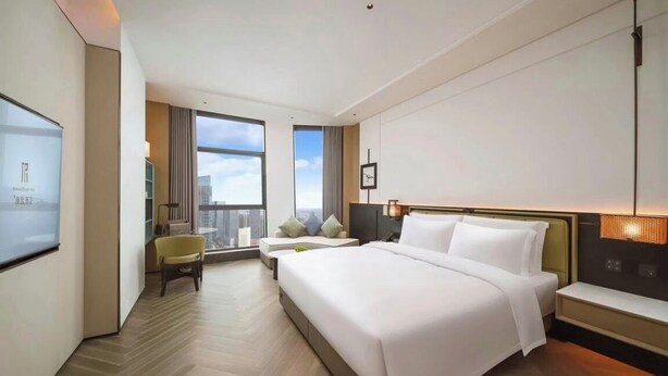 A hotel room with a large bed, a desk, a chair, a TV, and a city view. - Style INS High-Altitude River View Hotel (Chongqing)