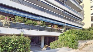 A modern building with multiple balconies, some with plants, and a paved entrance area. - Elegant Apt at Alimos Marina Sea View (Alimos)
