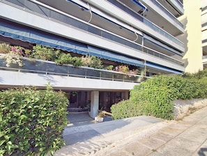 A modern building with multiple balconies, some with plants, and a paved entrance area. - Elegant Apt at Alimos Marina Sea View (Alimos)
