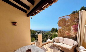 Ein Balkon mit einer Couch, Stühlen und einem Tisch, mit Blick auf eine reizvolle Landschaft.