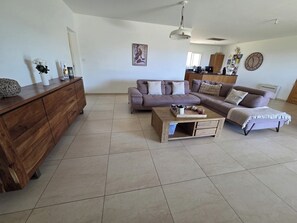 A living room with a wooden coffee table, two sofas, a wooden cabinet, and a wall clock. - Villa in the heart of nature with infinity pool, near Ajaccio... (Appietto)
