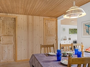 A dining area with a table set for two, a pendant light, and a view of a kitchen in the background. - "Haley" - 380m from the sea by Interhome (Hadsund)
