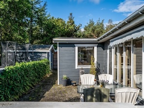 A compact, single-story building with a small patio area, a table with chairs, and a potted plant. - "Haley" - 380m from the sea by Interhome (Hadsund)