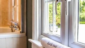 Ein Badezimmer mit Badewanne, einem Fenster mit Handtuch und einer Dusche.