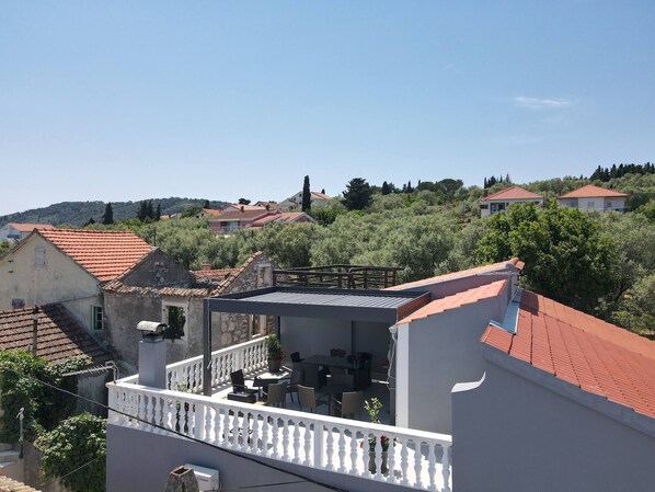 Ein Wohngebäude mit Balkon, rotem Ziegeldach und Blick auf umliegende Häuser und Grünflächen.