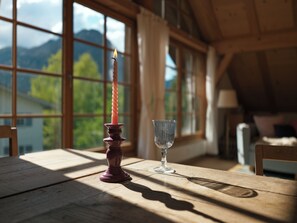 A candle on a wooden table by a window with a view of mountains. - Villa Senz - Happiness (Pfronten)