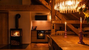 Una habitación acogedora con una estufa de leña, una mesa de comedor con velas y un televisor montado en la pared.