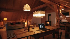 Un loft acogedor con vigas de madera a la vista, una mesa de comedor con una laptop, copas de vino y una vela.