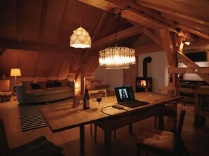 A cozy loft with exposed wooden beams, a dining table with a laptop, wine glasses, and a candle. - Villa Senz - Happiness (Pfronten)