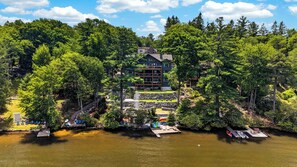 Ein Chalet am Seeufer mit Steg, Boot und einem Gebäude, das von dichtem Wald umgeben ist.