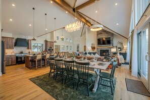 Een ruime keuken met houten kasten, een eethoek met stoelen, een kroonluchter en een open haard.