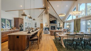 Een ruime keuken met een groot eiland, houten kastjes en een ingebouwde open haard.