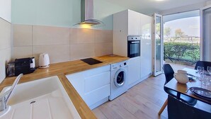 Eine moderne Küche mit Spüle, Waschmaschine und Backofen, sowie ein Essbereich mit Tisch und Stühlen.