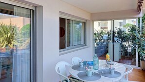 Een balkon met een tafel, stoelen, een raam en uitzicht op de omgeving.