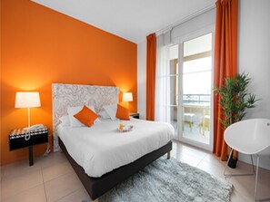 Ein modernes Hotelzimmer mit einem großen Bett, zwei Nachttischlampen, einem weißen Stuhl und Blick ins Freie.
