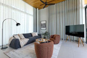 A modern living room with a sofa, coffee table, and a television on a stand. - Botanica Four Seasons Villas Tropiclook (Thep Krasattri)