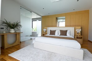 A modern bedroom with a large bed, wooden paneling, a bedside table with a lamp, and a potted plant. - Botanica Four Seasons Villas Tropiclook (Thep Krasattri)