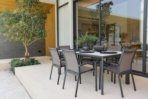 An outdoor dining area with a round table, six chairs, and potted plants. - Botanica Four Seasons Villas Tropiclook (Thep Krasatti)