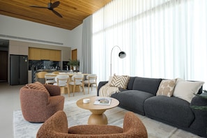 Een moderne woonkamer met een bank, stoelen, een salontafel en een eethoek met stoelen en een tafel.