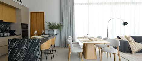 Una cocina moderna con una isla de mármol, armarios de madera y un comedor con mesa y sillas.