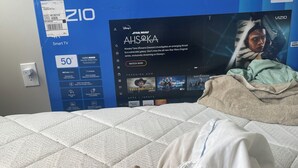 A bed with a white quilted mattress, a person lying down, and a TV box labeled 'VIZIO' with a Star Wars Ahsoka poster. - Charming barn in Annapolis for a relaxing getaway not a room just a mattress (Annapolis)