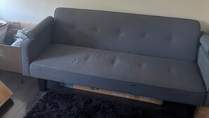 A grey sofa in a room with a plain wall and a black rug. - Charming barn in Annapolis for a relaxing getaway not a room just a mattress (Annapolis)