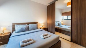 Ein Hotelzimmer mit einem großen Bett, Nachttischen, einem Spiegel und einem Fenster.
