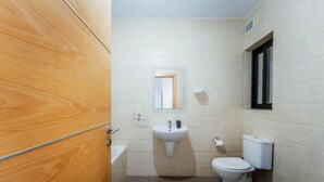 Ein Badezimmer mit Holztür, Waschbecken, Toilette und Spiegel.