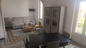 Ein Essbereich mit Tisch und Stühlen, einer Couch, einer Lampe und Blick ins Freie.