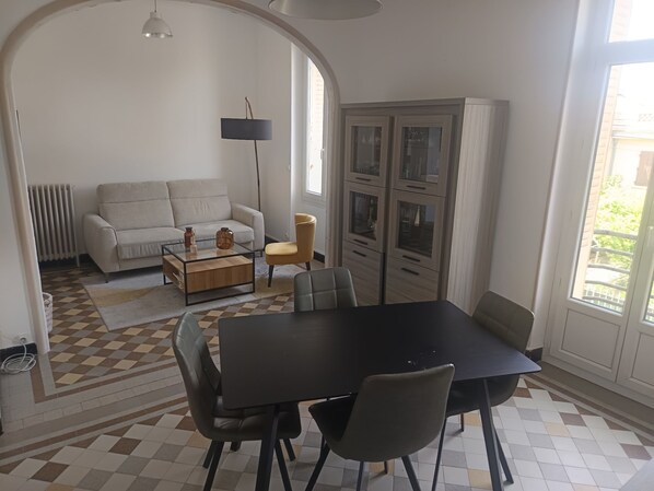 Un comedor con una mesa y sillas, un sofá, una lámpara y vistas al exterior.