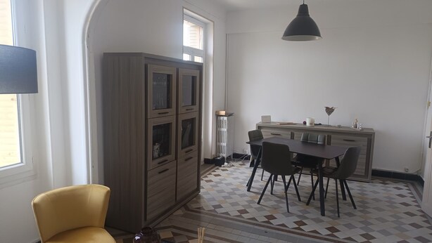 Ein Zimmer mit Esstisch, Stühlen, einem Schrank, einer Couch und einer Lampe.