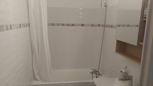 Ein Badezimmer mit Badewanne, Dusche, Waschbecken und Spiegel.