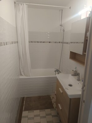 Un baño con bañera, ducha, lavabo y espejo.