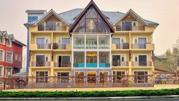 A multi-story hotel with a central glass facade, balconies, and a gated entrance.