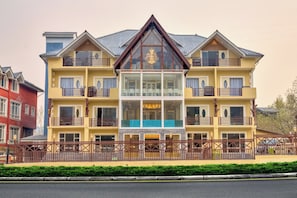 A multi-story hotel with a central glass facade, balconies, and a gated entrance. - The Pahalgam Dayz (Pahalgam)