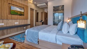 Un dormitorio moderno con una cama grande, un televisor montado en la pared y un baño visible a través de un separador de vidrio.