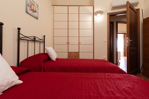Une chambre avec deux lits, une armoire et un tableau au mur.