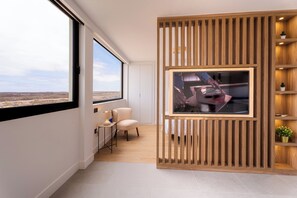 Une pièce moderne avec une grande fenêtre, un mur recouvert de panneaux en bois, un tableau encadré, une chaise et une petite table.